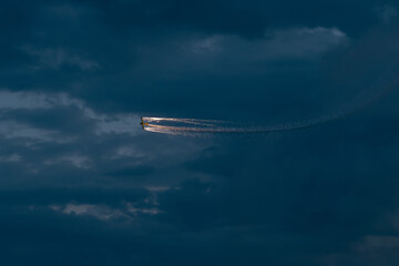 Stunt Plane performing with smoke and fireworks in stormy evening