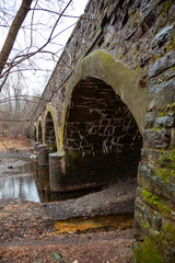 Elements of the ancient stonework of the eight-arch bridge, overgrown with moss and lichens, in  Dark Hollow Park, Pennsylvania, USA