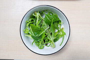 A bowl of fresh green salad leaves.