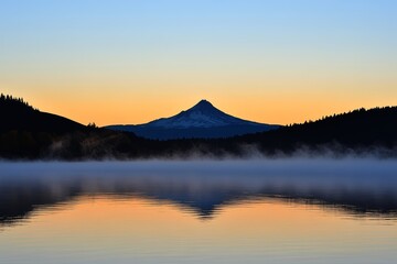 Obraz premium A tranquil lake reflects the stunning silhouette of a snow-capped mountain during a peaceful early morning at dawn