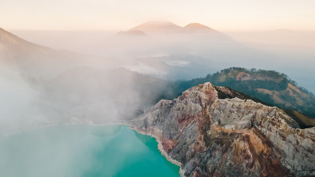 Aerial view of Ijen volcano with a scenic sulfur lake surrounded by mist and clouds at sunrise, Kawah Ijen, Java, Indonesia.