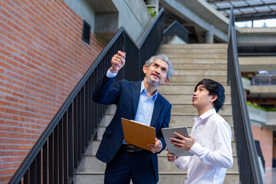 Asian senior professor is giving advice  to the college student on the research thesis while sitting in the university faculty for education, academic and business concept