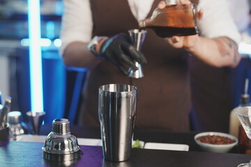  bartender mixes cocktails with syrup and shakes them on the counter.