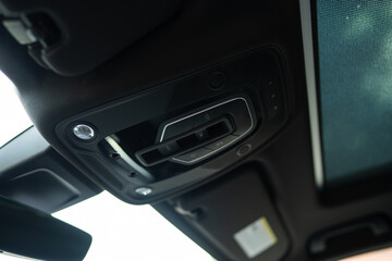 Close up view of interior cabin lights with dome-shaped cover attached to ceiling of modern car. Overhead controls of turning on or off illumination in cabin of vehicle