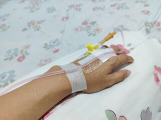A close-up of a person's left hand being given an IV drip at the top of his hand. Transparent IV...
