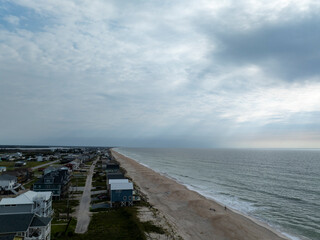 Aerial photo above the shore.  Sunrays come through a cloudy sky.