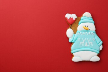 Tasty Christmas cookie in shape of snowman on red background, top view. Space for text
