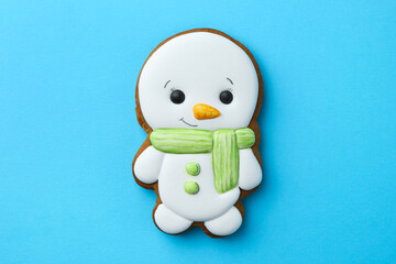 Tasty Christmas cookie in shape of snowman on light blue background, top view