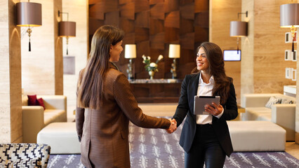 Two businesswomen gather in the office lobby to talk about their business plans	
