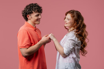 Love confession. Happy couple stands on pink, holding hands, look into eyes. Romantic feelings, perfect relationships.