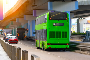 Double-decker city shuttle bus drives along route line among buildings on the street under the bridge road junction metropolis