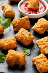 Homemade crispy fried chicken nuggets served on a stone board