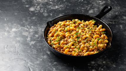 Cheeseburger Pasta with ground beef, melted cheese and gherkins in a iron cast pan
