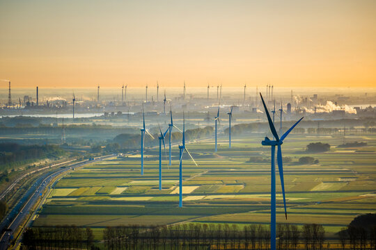Aerial View on Waasland rural area mixed with wind turbines and harbor of Antwerp in the background during sunrise
