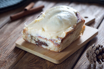 A bun with chocolate and cinnamon lies on a board on the table