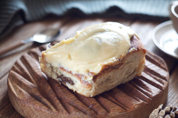 A bun with chocolate and cinnamon lies on a board on the table