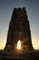 Sunburst through the archway of a historic Glastonbury Tor tower at sunrise © PetrDolejsek