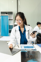 Successful female doctor standing at table, looking at camera.