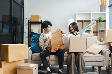 Young couple relaxing sitting on the floor around cardboard boxes at home, smiling happy moving to a new house.