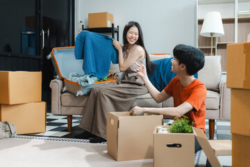 Successful young couple is moving to a nice new place, around boxes with their belongings. The room is very bright and bright, they are wearing casual clothes.