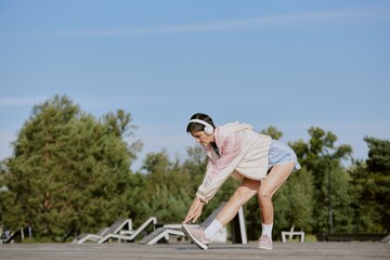 Senior sporty woman doing forward bend wnile listening to music