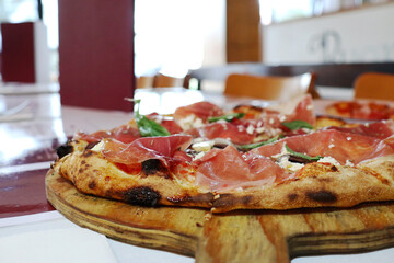 delicious pizza on a wooden stand on a table in a cafe