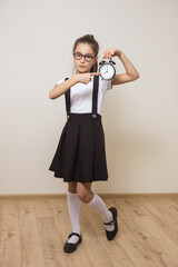 girl schoolgirl with an alarm clock her hands