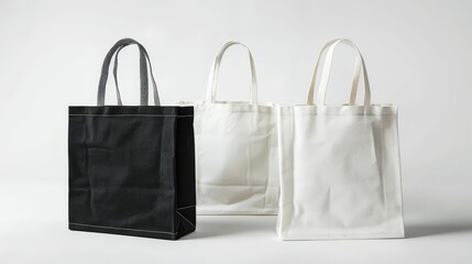 Three blank tote bags, black, white, and cream, isolated on white background.