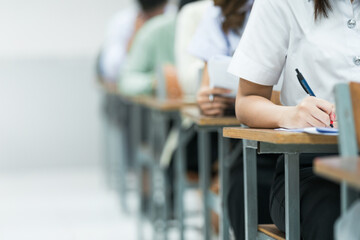 Students Taking Exam in Classroom Setting. Students in uniforms are seated in a classroom, writing...