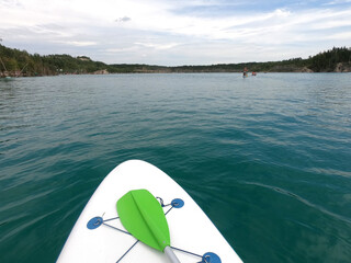 SUP board floating on the surface of the blue water of a quarry lake with rocky shores and trees...