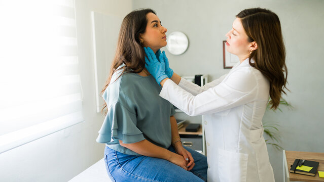 Doctor gently palpates a young woman's lymph nodes during a medical examination