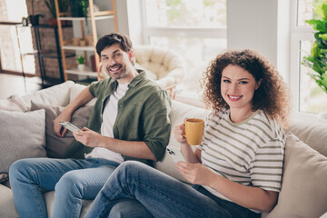 Obraz premium Photo of two young people use phone drink coffee modern interior apartment indoors