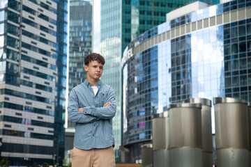A young man stands at the Moscow City towers and looks into the distance