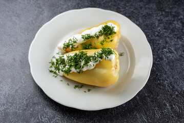 Two small yellow peppers with a white sauce on top of a white plate