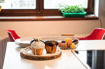 Three Easter cakes and painted eggs in the basket on the table and green pea seedlings on the windowsill.