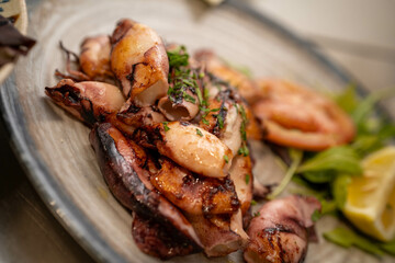 Detailed close-up of grilled squids. Perfect for food styling blogs or product promotions targeting seafood enthusiasts and high-end dining establishments.