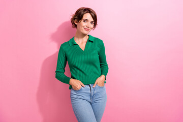 Photo of pleasant gorgeous girl with bob hairdo dressed green shirt standing holding arms in pockets isolated on pink color background