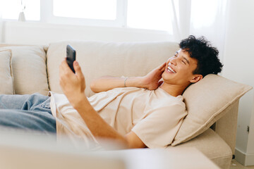 relaxation, happiness, leisure, technology, communication A young man relaxing on a light colored...
