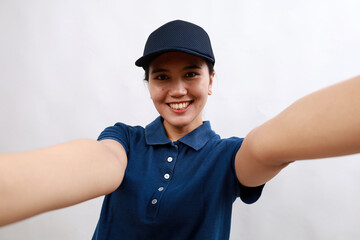 Young hispanic woman courier wearing delivery uniform and cap looking at the camera smiling with open arms for hug. cheerful expression embracing happiness.close up