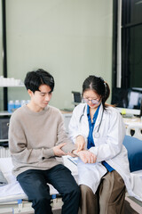 Obraz premium Asian male patient on bed while doctor hands of checking examining his pulse for record the treatment results