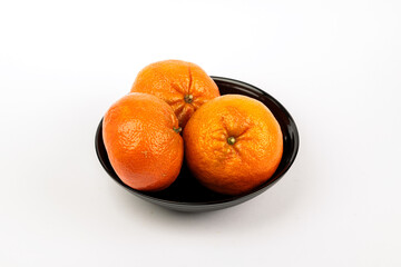 Three tangerines in a black fruit bowl on a white background.