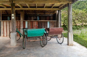 Old cycle rickshaws parked under a house in Kampot in Cambodia