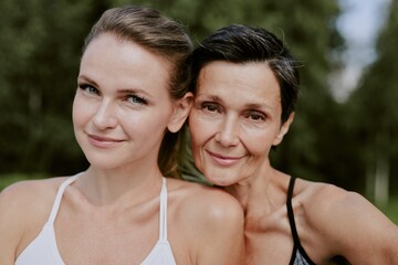 Medium close up portrait of smiling adorable mother and daughter looking directly at camera