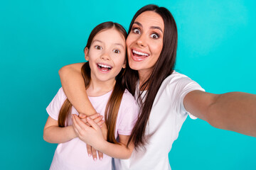 Photo of cheerful glad girl with mommy having fun selfie wearing white trendy clothes isolated on cyan color background