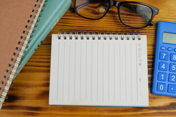 education and back to school concept. alarm clock, scissors, colorful pens, and paper clips over yellow background. top view, flat lay. blank white paper for text space. 