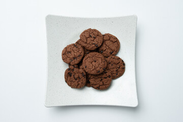 Chocolate chip cookies are piled on a white plate