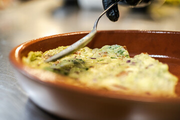 A creamy and fresh guacamole sauce served in a plate, featuring mashed avocados, finely diced tomatoes, onions, and cilantro. A vibrant green dip, perfect for pairing with chips or meals.