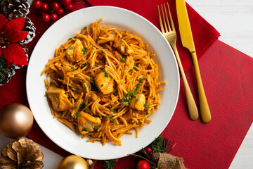 Spanish paella with fideuá and vegetables and chicken. Top view table with Christmas decoration.