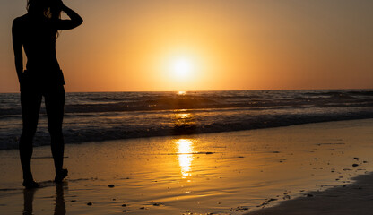 Silhouette of a woman watching the sunset on the beach © Raquel