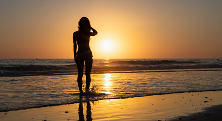 Woman standing on the beach during sunset